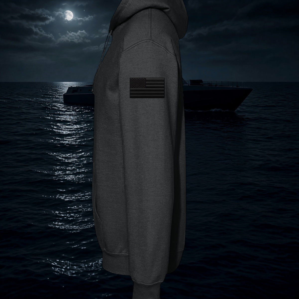 Better Grab A Beer black fleece hoodie with a tonal American flag patch on the sleeve against a night ocean backdrop.